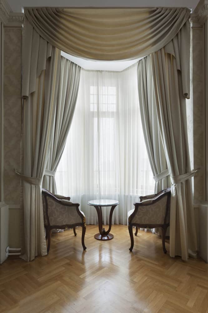 Classic drapes in bay window with antique chairs