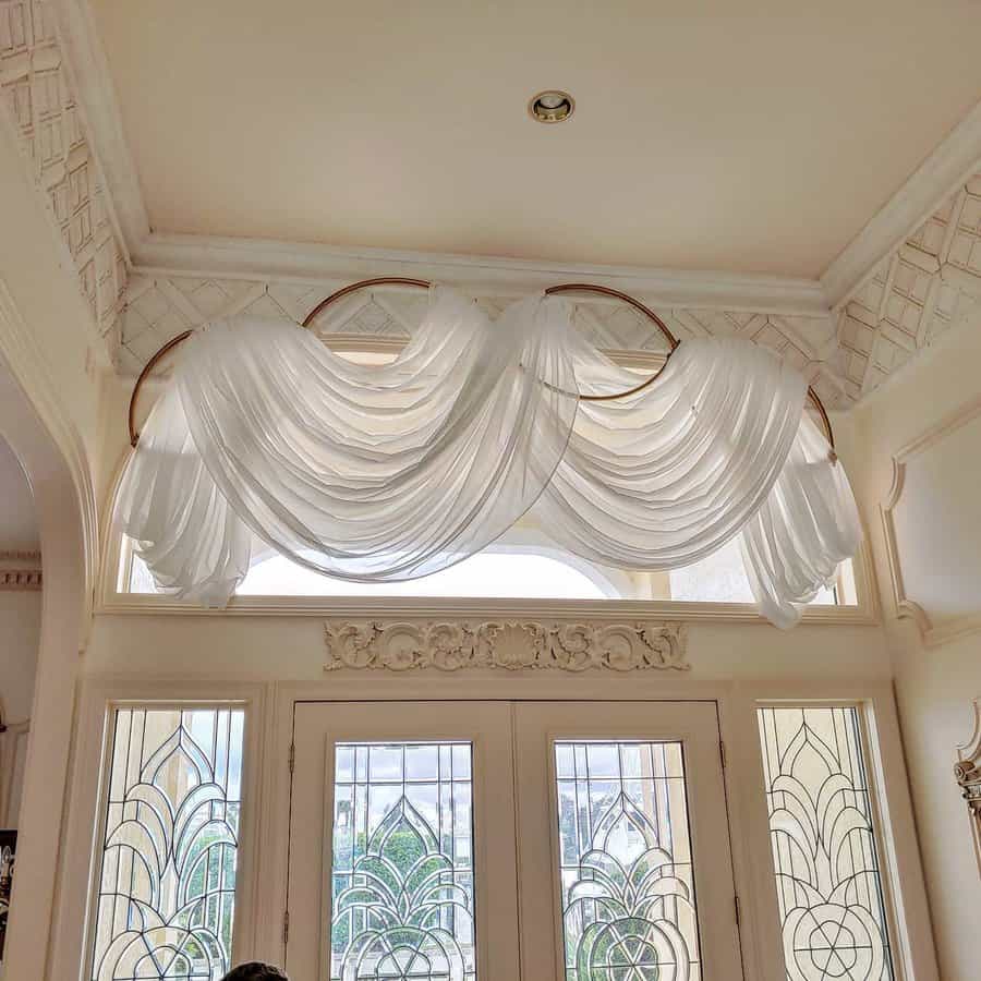 Luxurious swag curtain over ornate glass doors