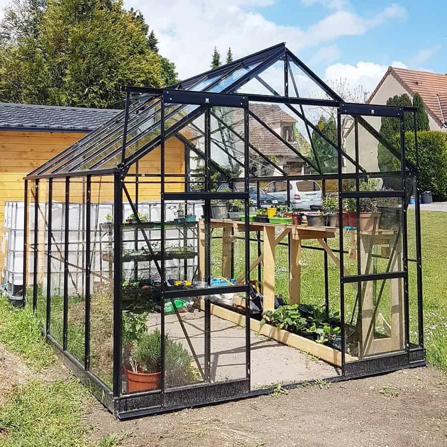 Open a black metal greenhouse with plants on a sunny day