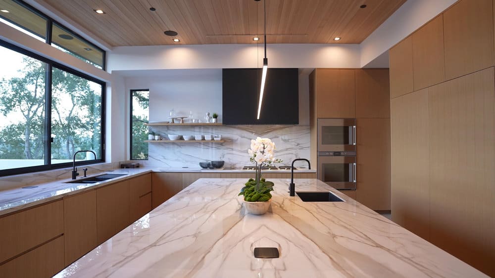 Streamlined kitchen with wood tones and linear pendant light