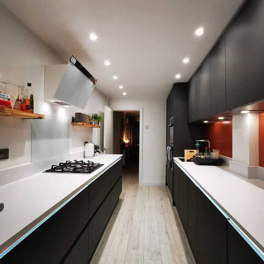 Galley Kitchen With Maple Wood Flooring And Black Cabinets