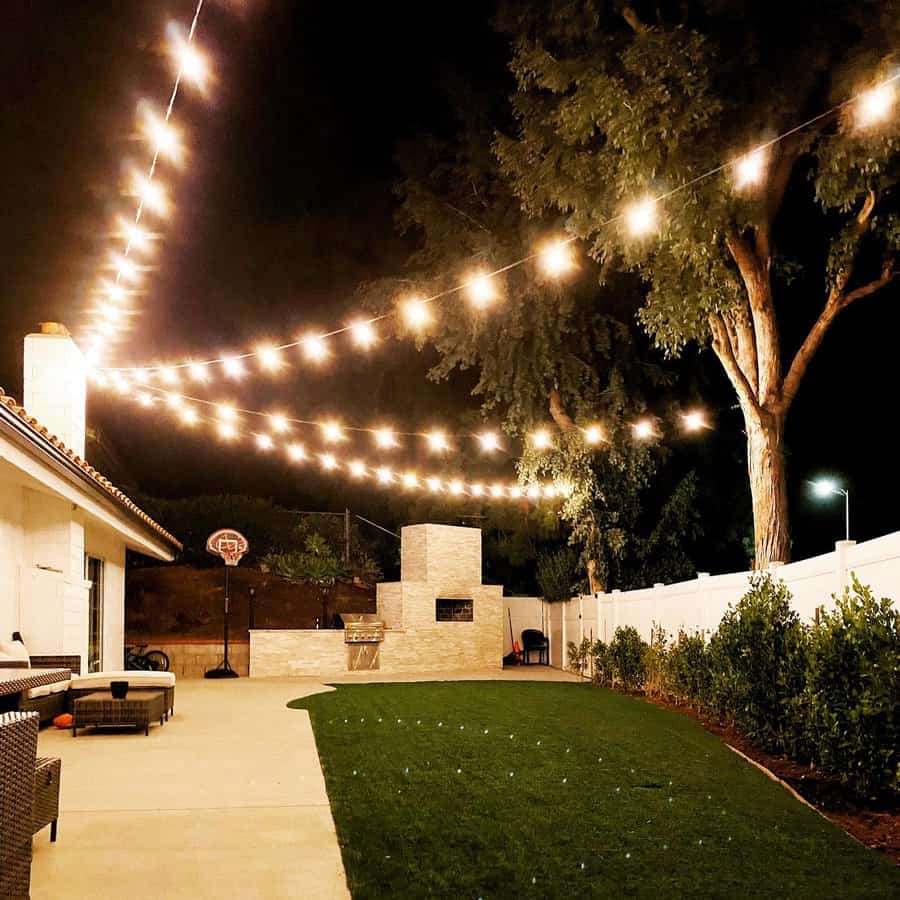 Backyard with hanging lights from fire chimney to trees 