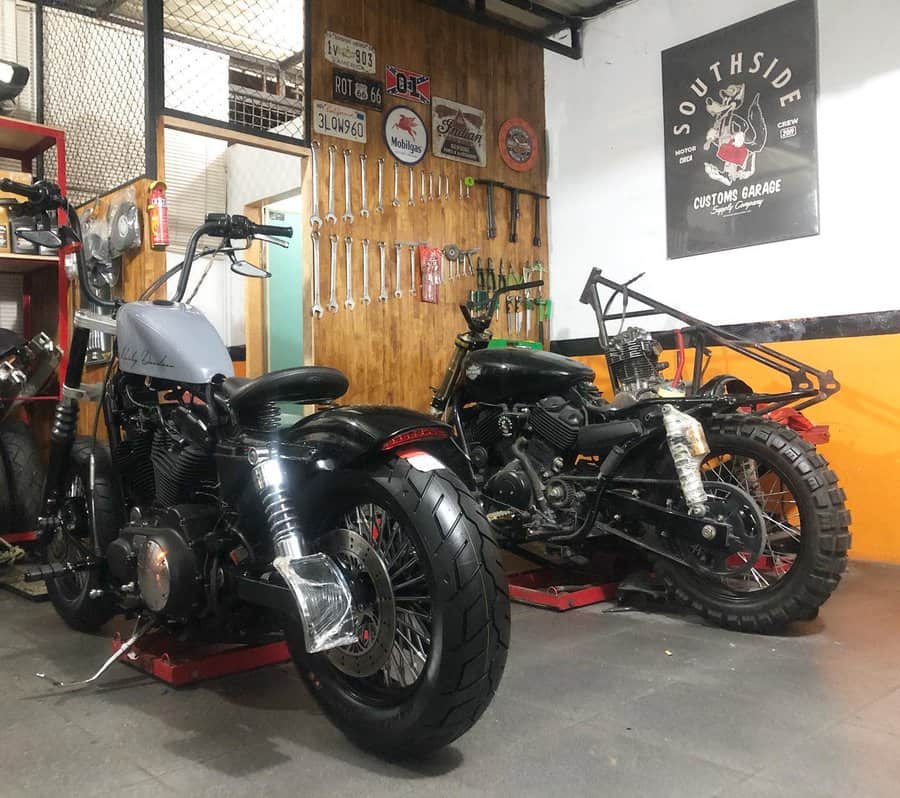 Two motorcycles parked in a garage with organized tools hung on the wall