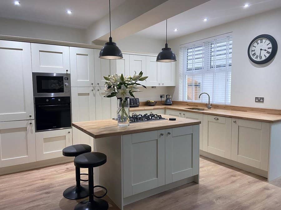 Contemporary kitchen with industrial lights and white cabinetry