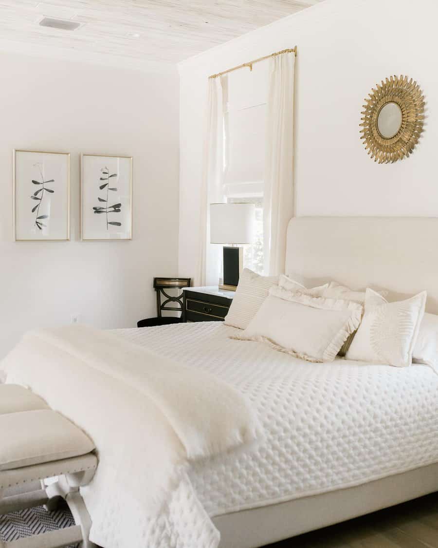 Minimalist bedroom with botanical prints and a sunburst mirror