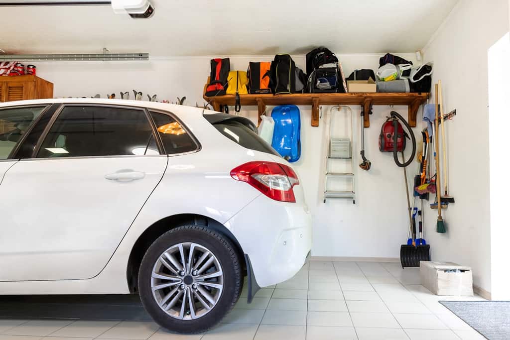 Organized garage interior with a white car and wall mounted storage