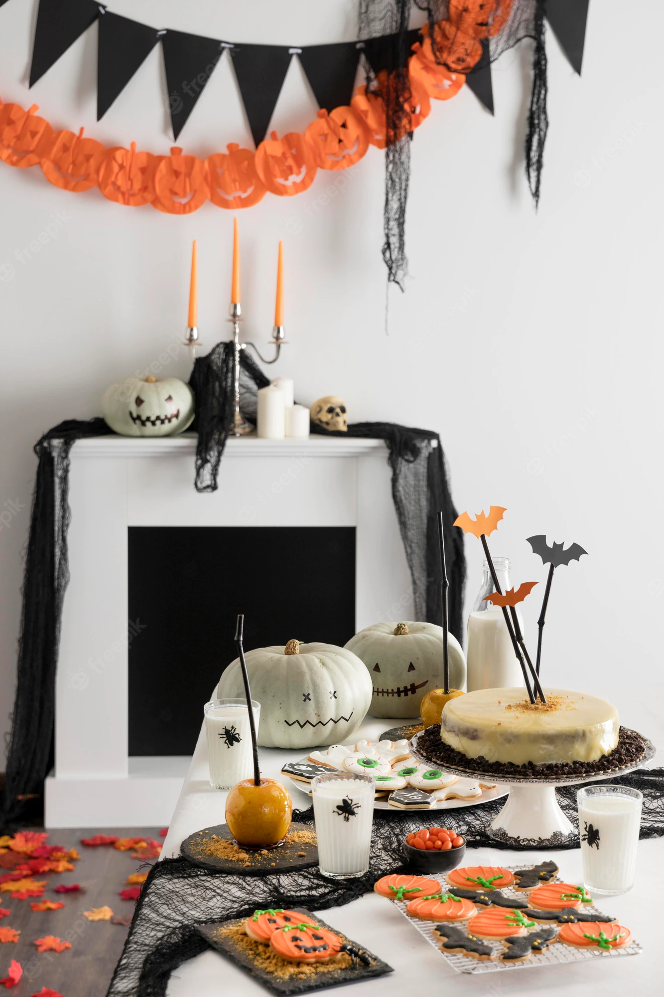 Halloween-themed table spread with pumpkin decor, treats, and black-orange banners