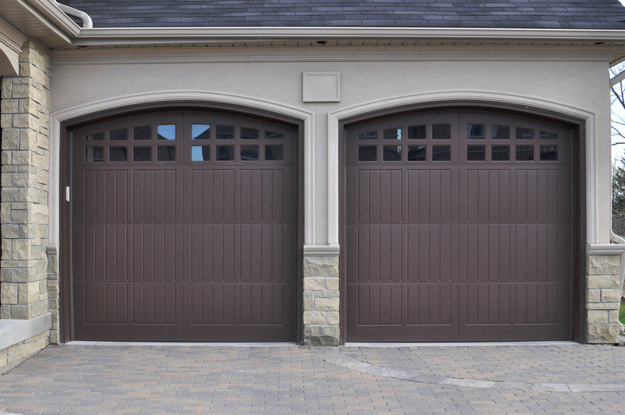 Twin brown garage doors with upper window panels