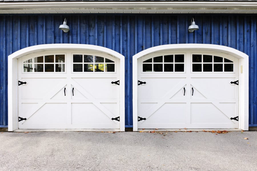 White arched garage doors on a blue facade with lamps
