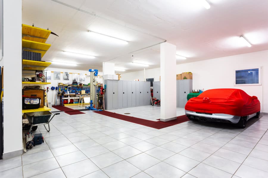 Spacious garage with car under red cover and storage shelves