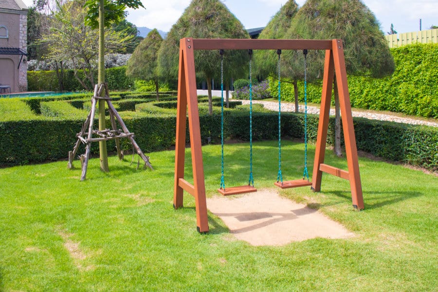 Wooden swing set in a manicured garden with lush grass