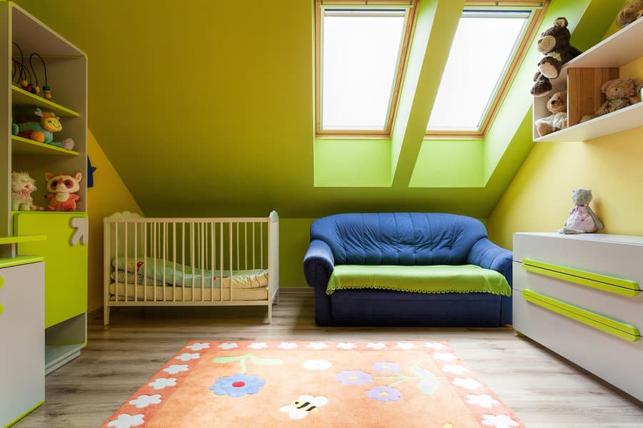 Colorful attic nursery with green walls and blue sofa
