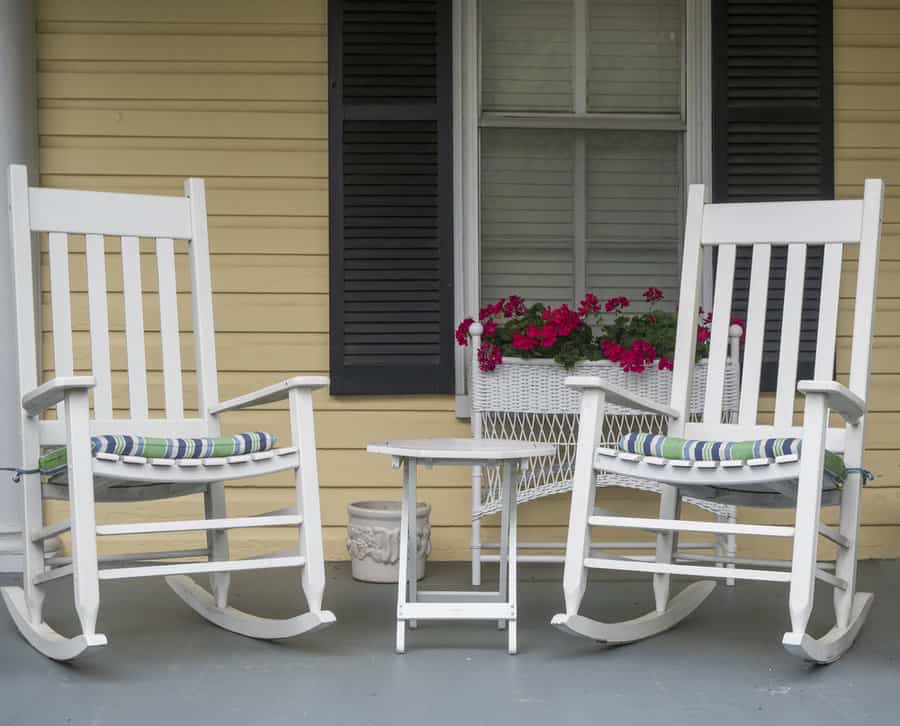 Two classic American rocking chairs on the front porch of a home.
