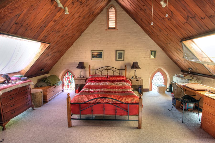 Cozy attic bedroom with wooden ceiling and red bedspread