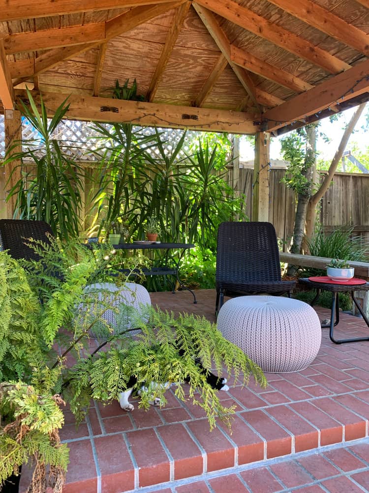 Covered patio nook with seating and lush greenery