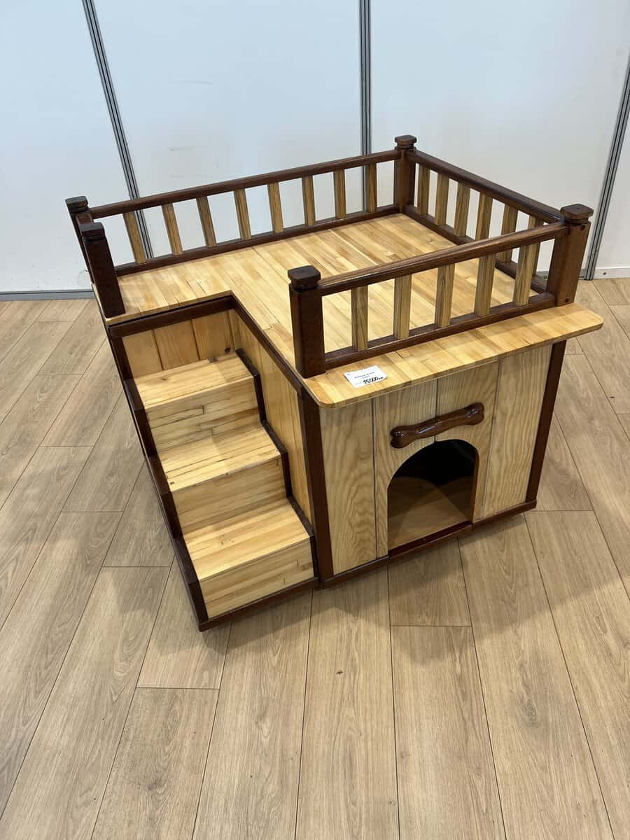 Stylish wooden dog house with built-in stairs and a rooftop balcony, perfect for lounging or napping in a cozy indoor space.