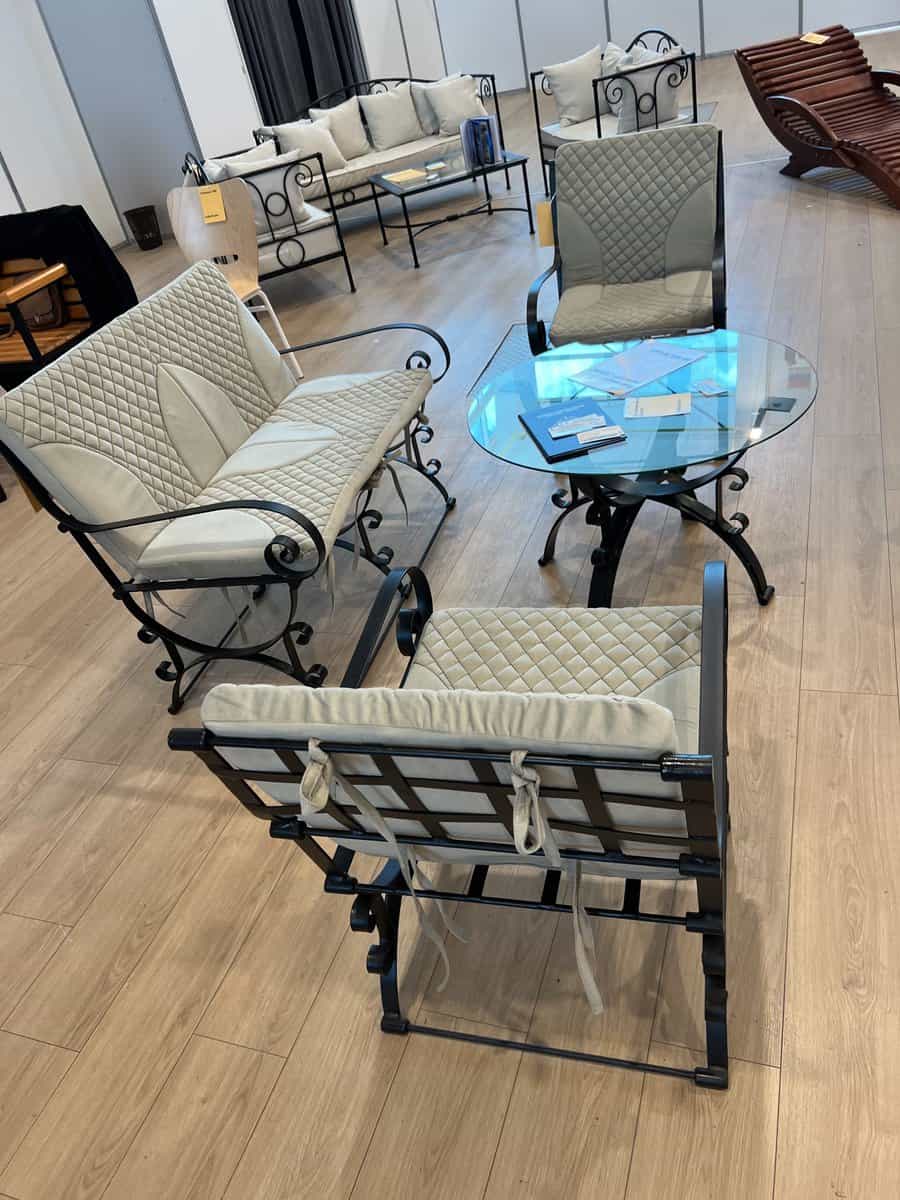 Metal patio furniture set with quilted cushions, including two chairs, a bench, and a glass-top table