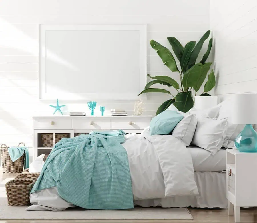 Bright coastal-themed bedroom with white shiplap walls, turquoise accents, and tropical plant decor.