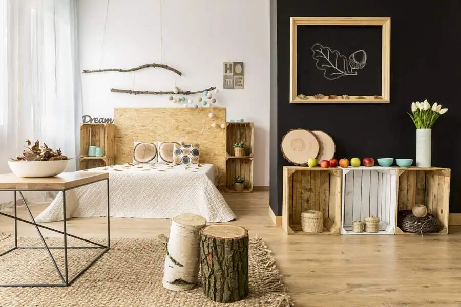 Rustic bedroom with a DIY wooden headboard, natural decor elements, black accent wall, and wooden crate storage.