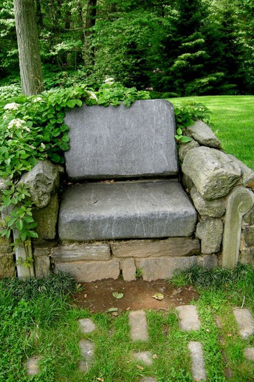 Stone bench surrounded by green foliage in a garden setting