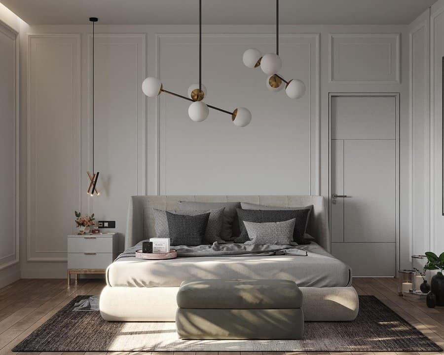 Modern bedroom with grey upholstered bed, geometric pendant lights, and minimalistic decor.