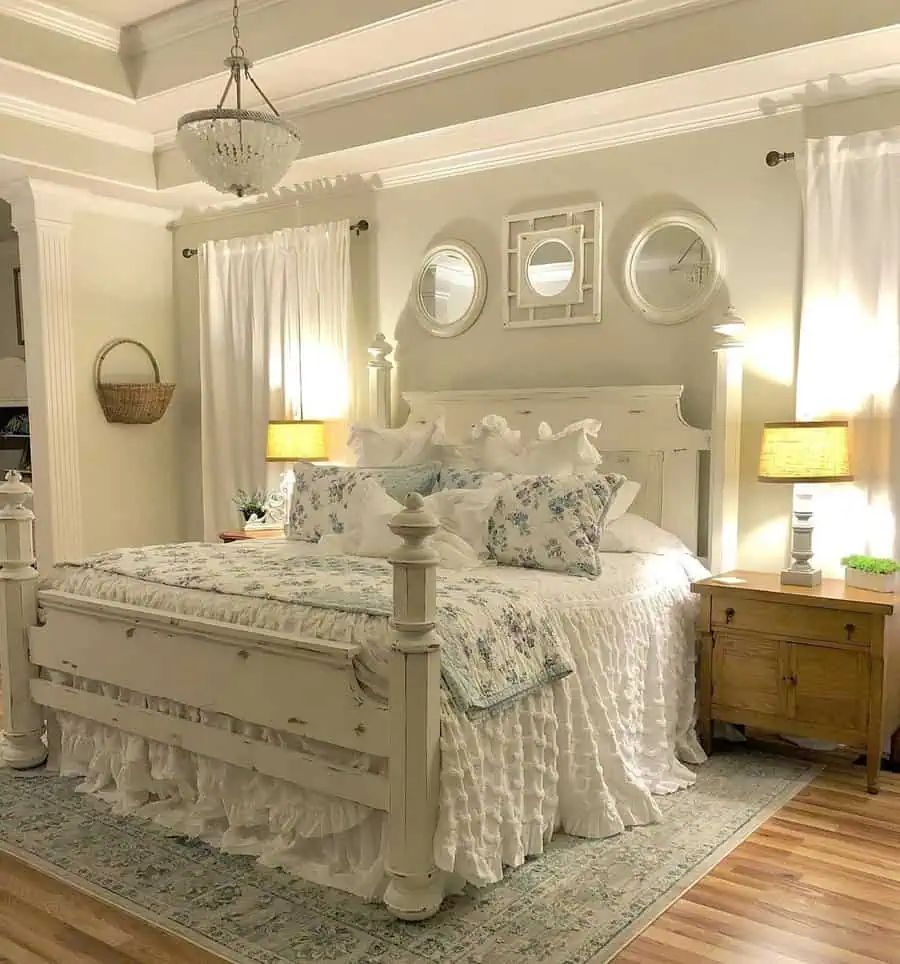 Traditional bedroom with white wooden bed frame, floral bedding, chandelier, and rustic decor elements.