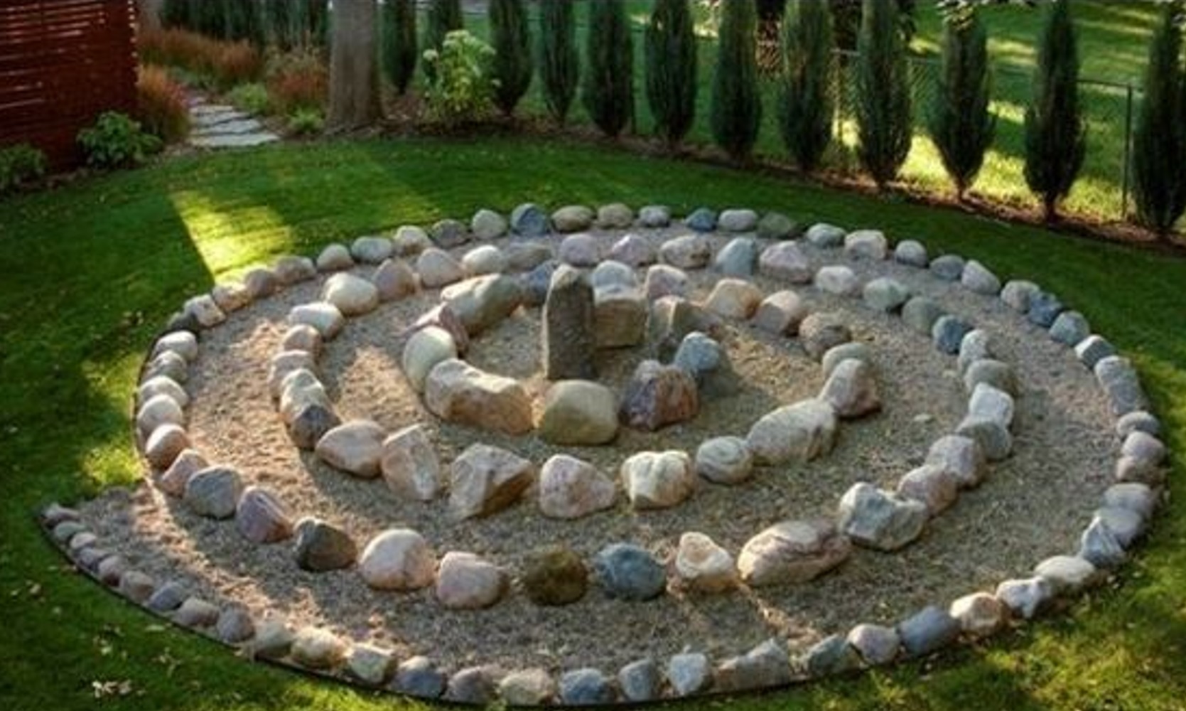 Stone circles arranged concentrically in a garden with green grass and trees