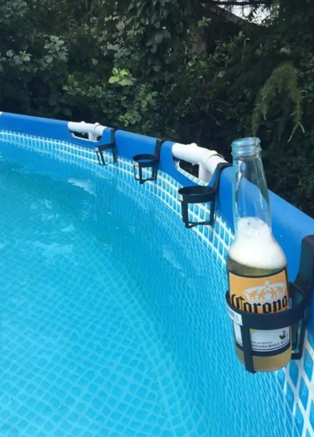 A bottle of beer held by a drink holder on the side of a pool.