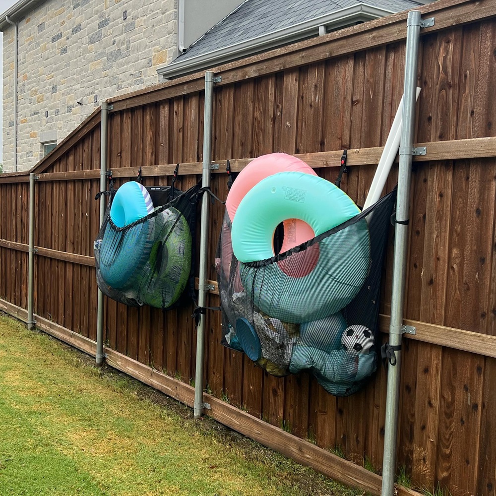 Inflatable toys and sports equipment stored in mesh nets on a wooden fence.