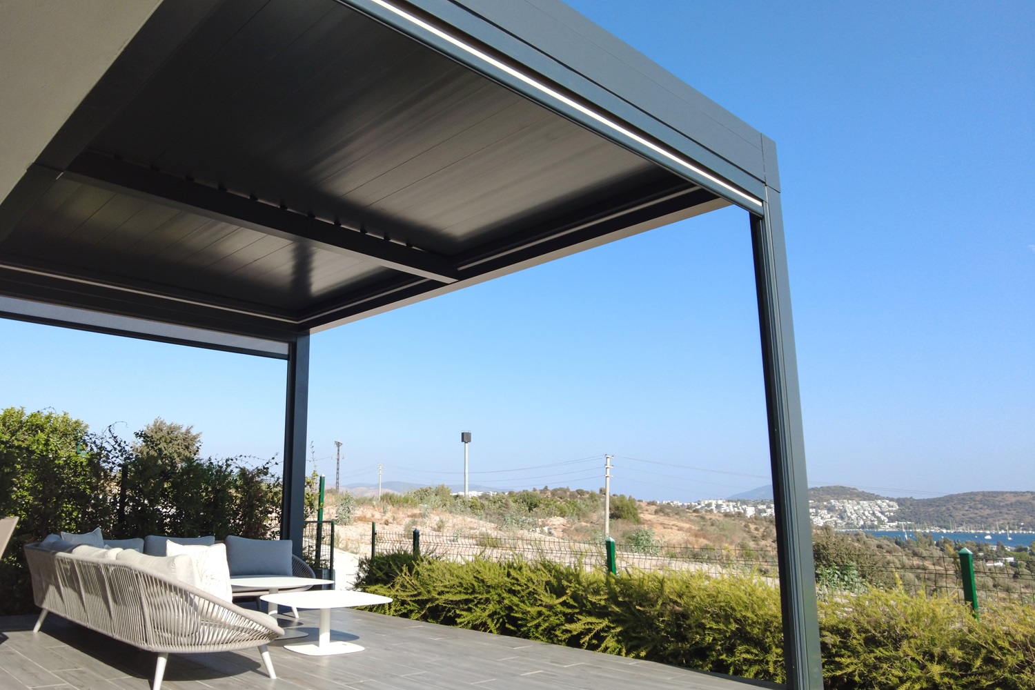 Modern outdoor patio with sofa overlooking a coastal landscape and blue sky