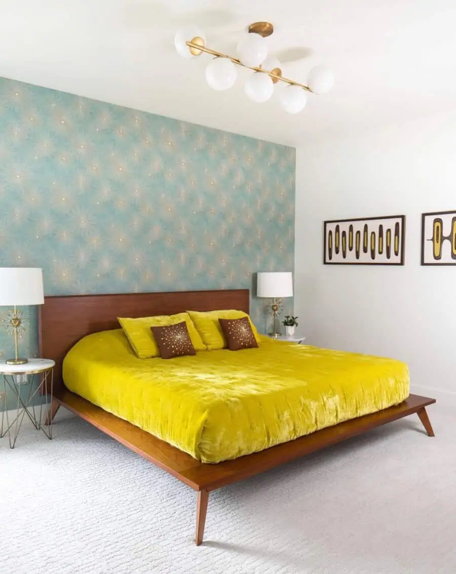 Retro-inspired bedroom with teal patterned wallpaper, mustard yellow bedding, and mid-century modern furniture.