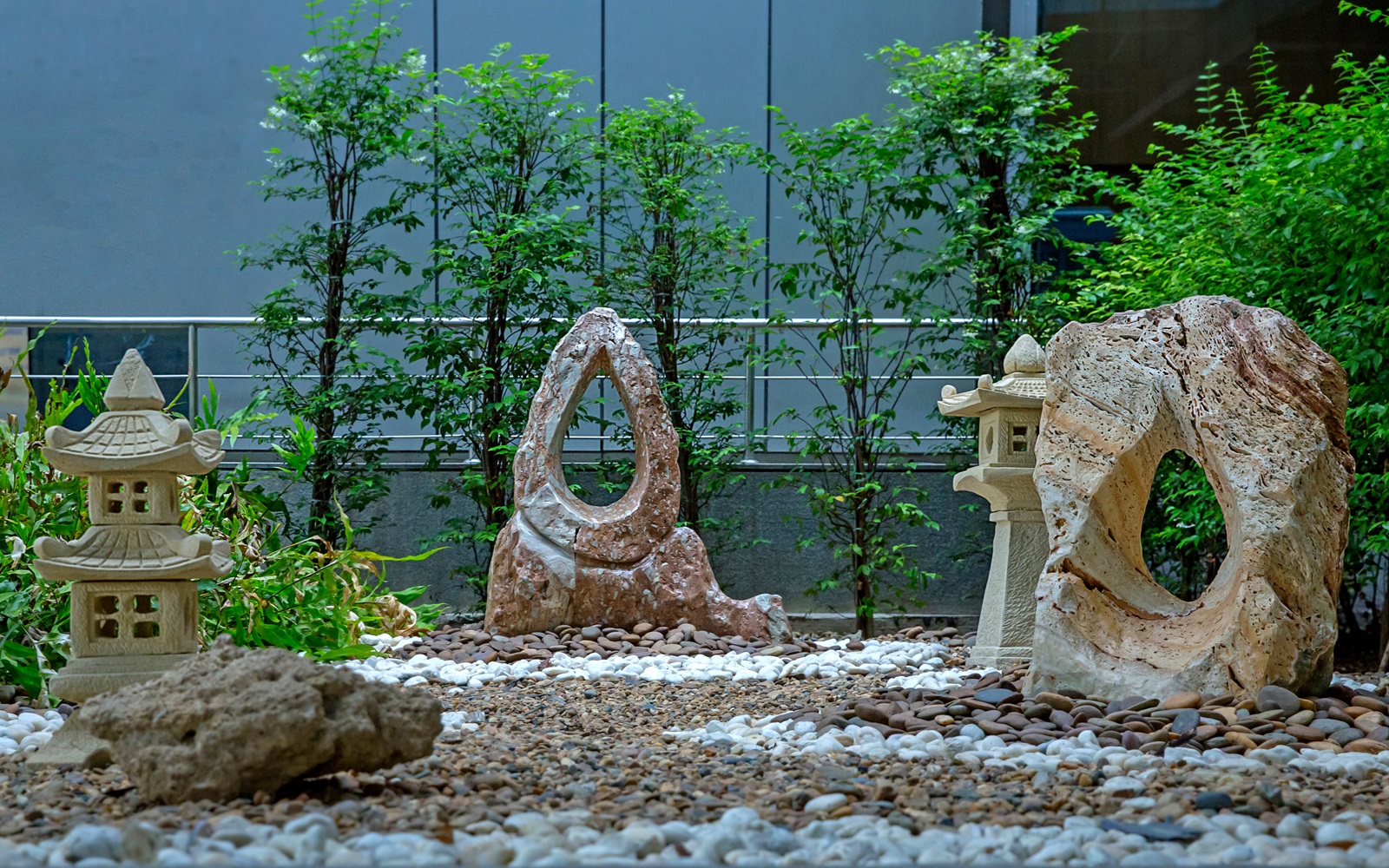 A serene Zen garden with statues, rocks, and greenery