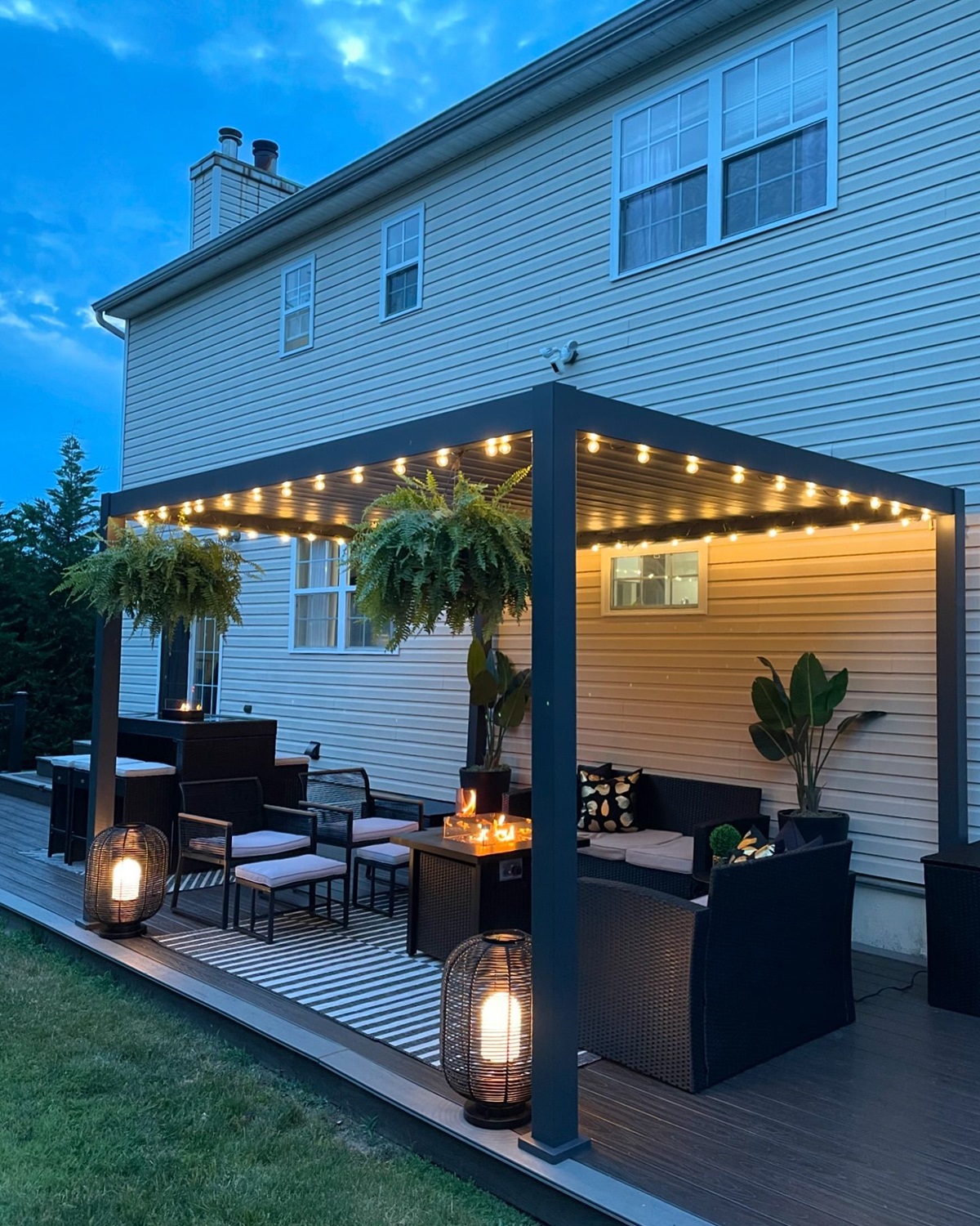 Illuminated patio with cozy seating, hanging plants, and lanterns in the evening