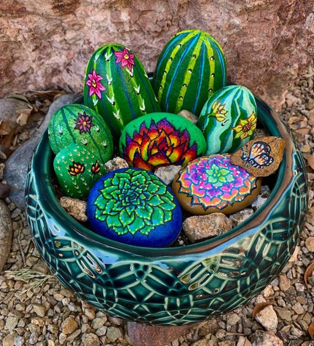 A ceramic bowl containing colorful painted stones resembling cacti and flowers