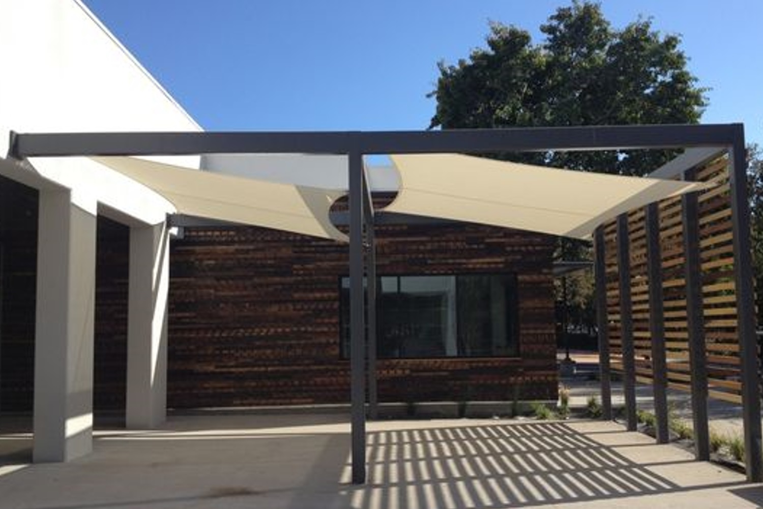 Modern pergola with stretched fabric sails providing shade over an outdoor patio