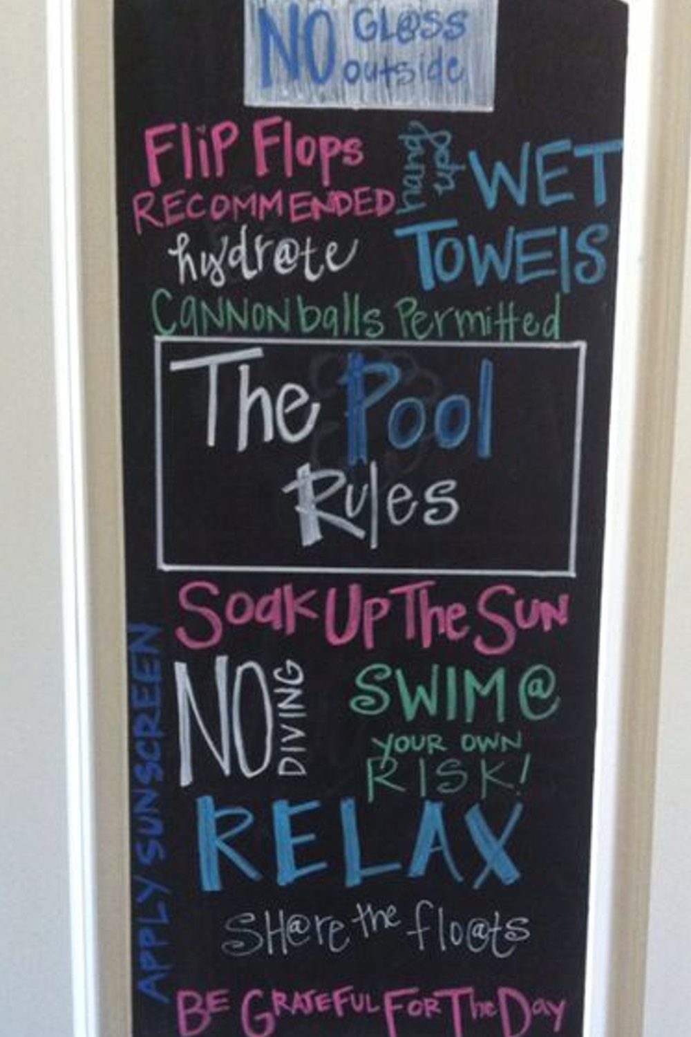 Chalkboard pool rules with colorful text and phrases, such as "swim at your own risk" and "relax.