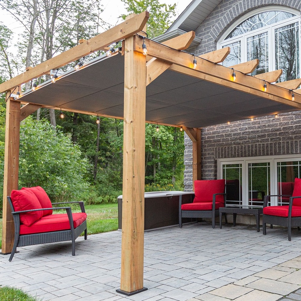 Wooden pergola with string lights, red cushioned seats, and a brick house in the background