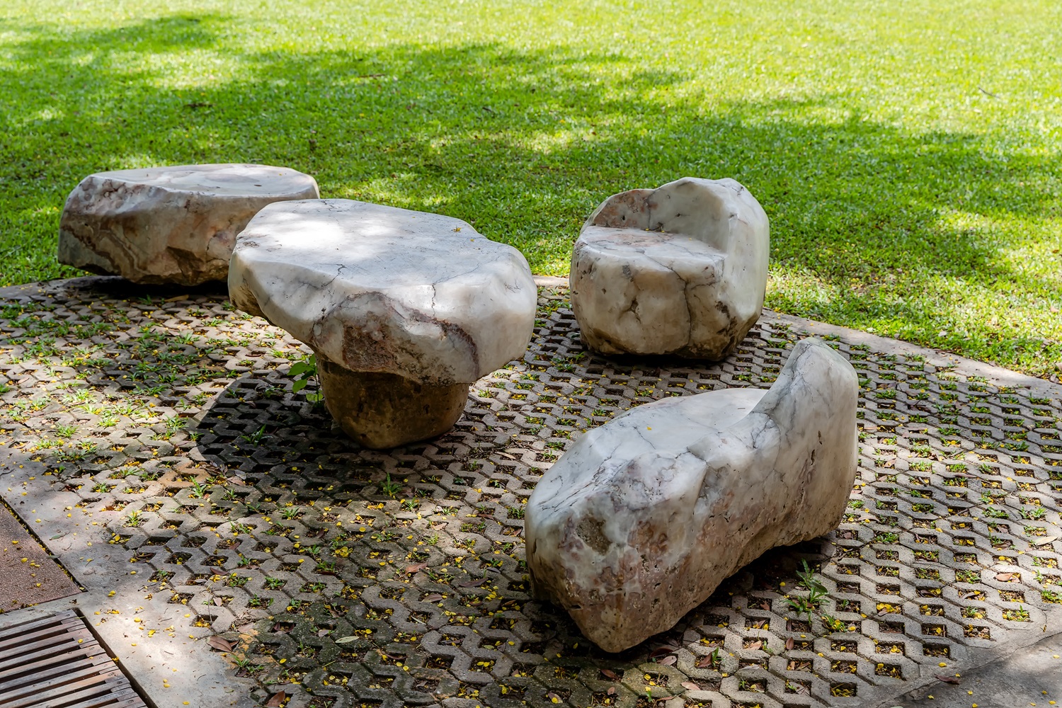 Stone table and seating set on paved ground in a grassy outdoor area