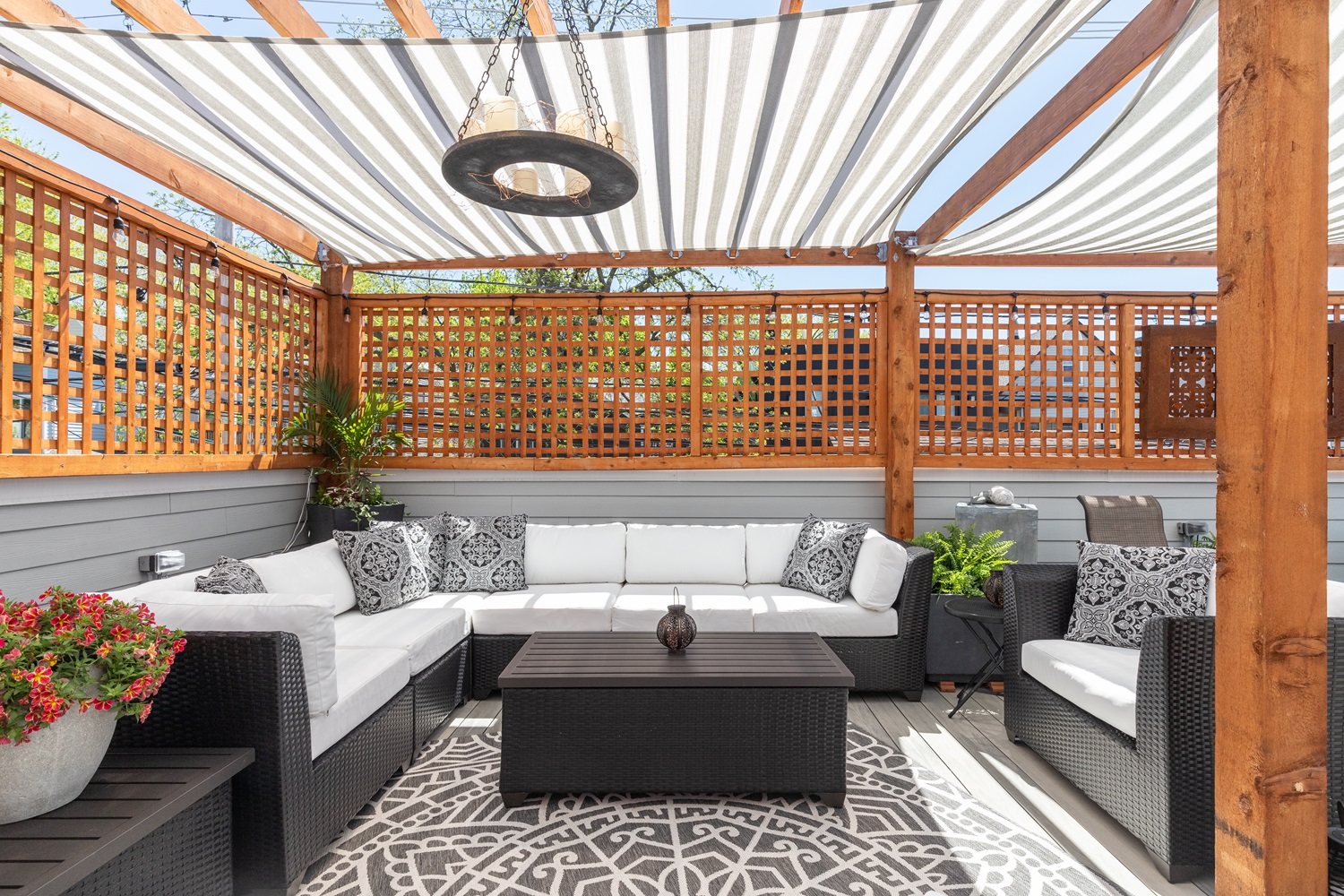 Outdoor patio with sectional seating, patterned rug, and pergola with striped shade