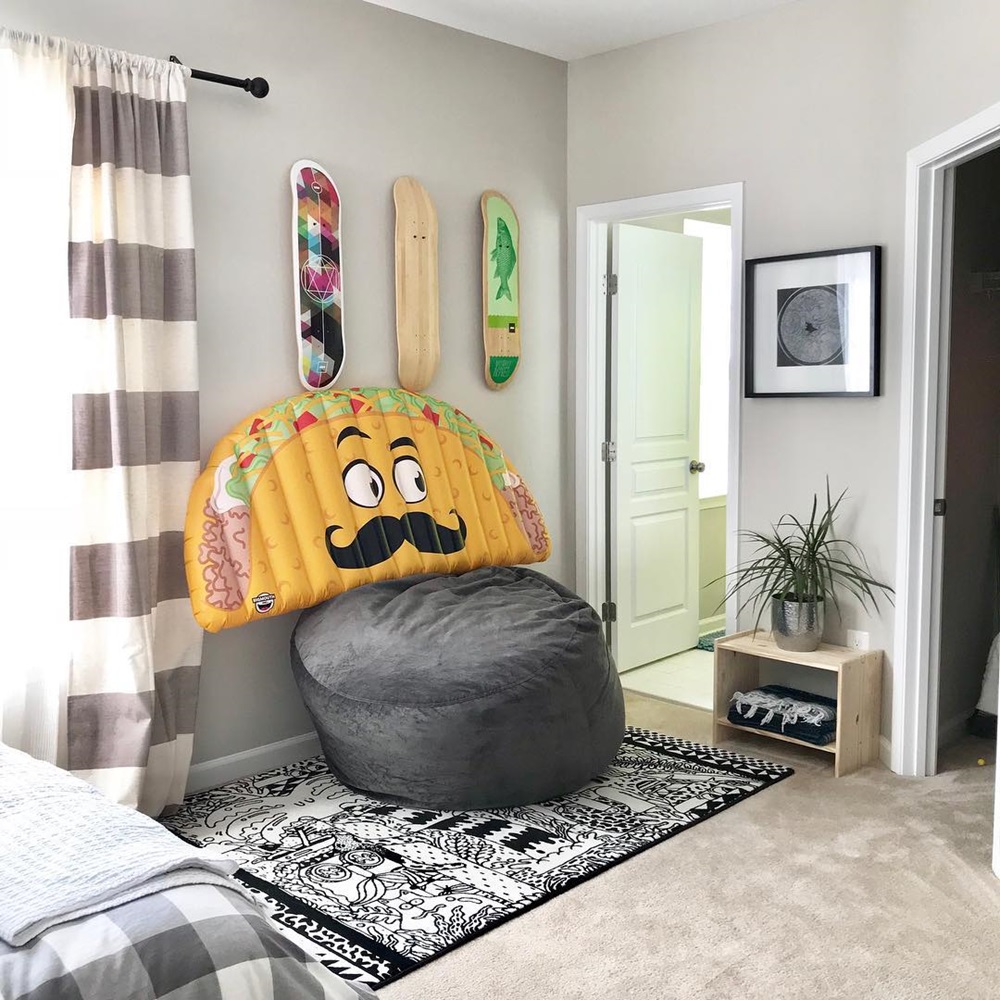 A taco-shaped pillow on a bean bag in the corner, and skateboards mounted on the wall in a bedroom