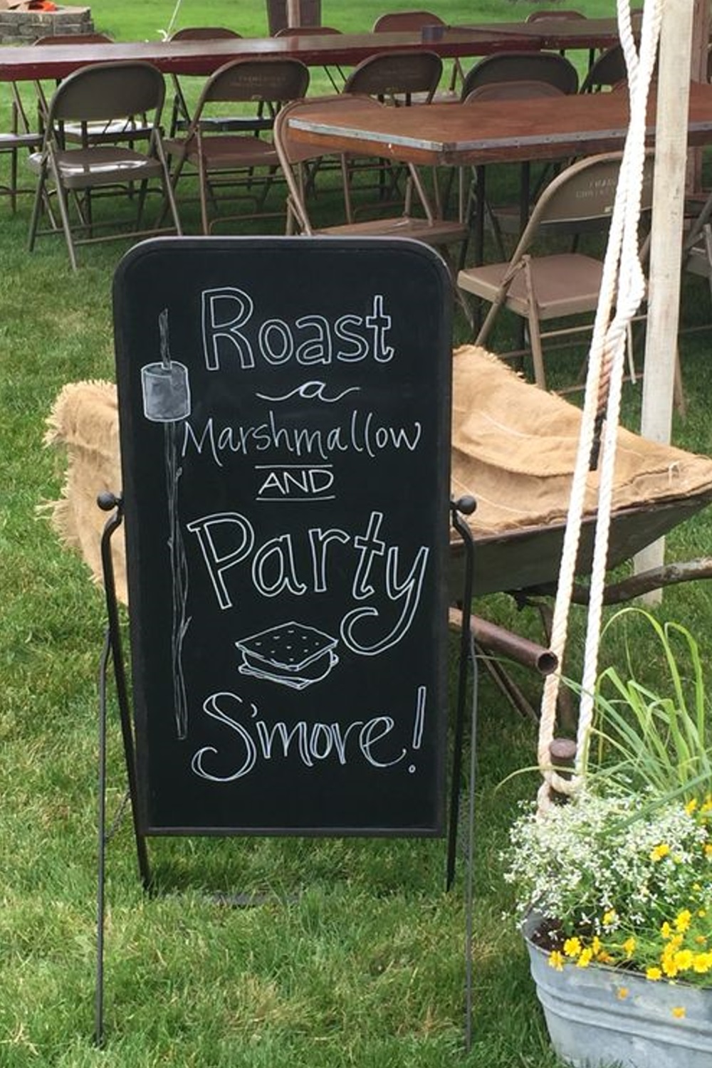 Chalkboard sign inviting to roast marshmallows and make s'mores at an outdoor event.