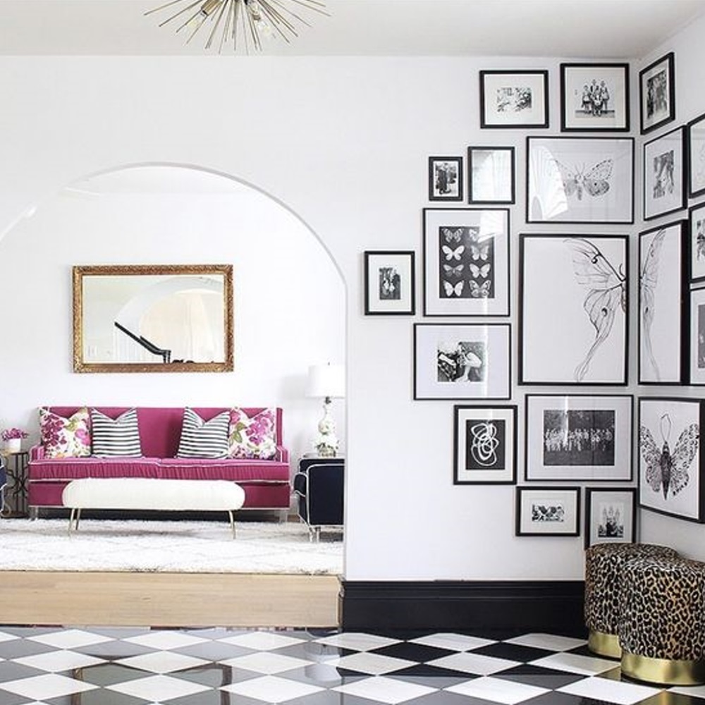 Modern living room with black and white photos, pink sofa, and checkered floor