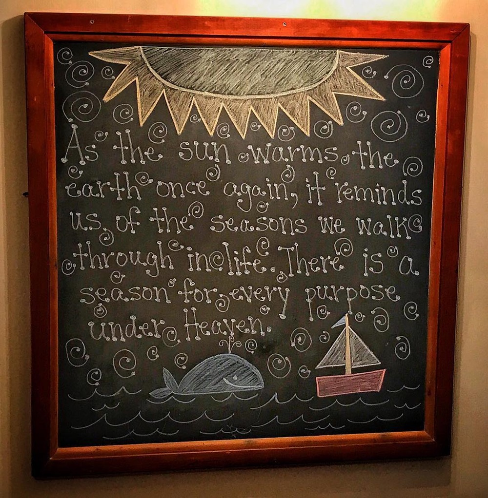 Chalkboard with a quote, sun, ocean waves, a boat, and a whale illustration.