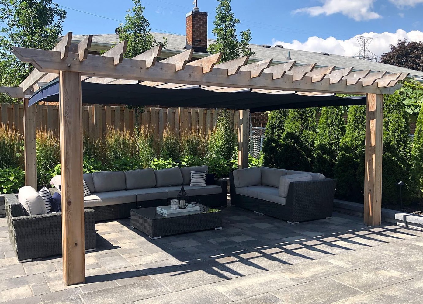 Outdoor patio featuring a wooden pergola and wicker furniture set on a stone floor