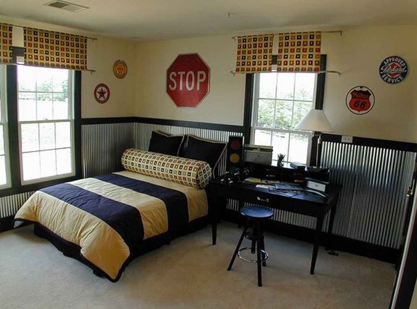 A bedroom featuring a single bed, a desk, and multiple road signs decorating the walls