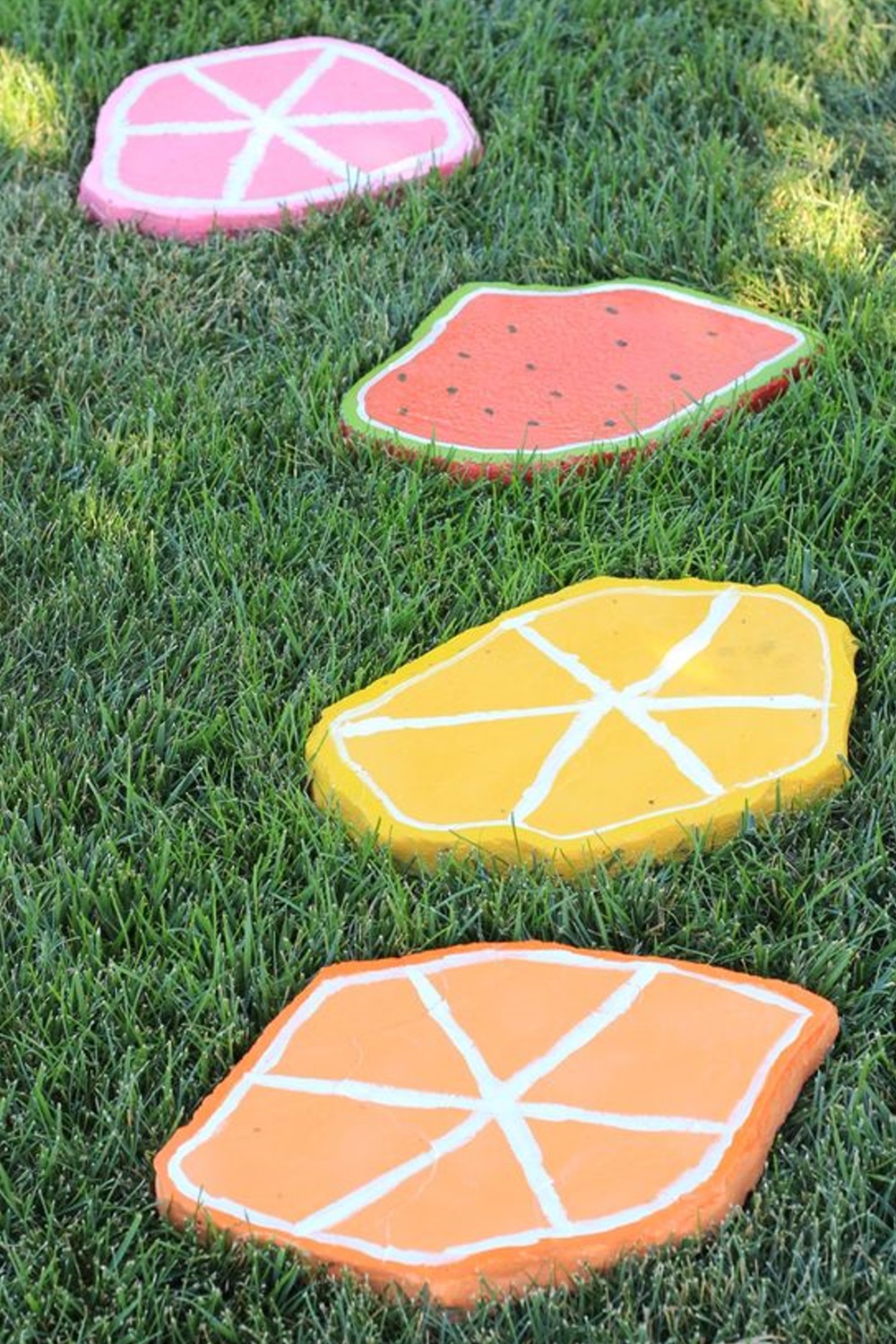 Citrus and watermelon slice painted stepping stones on grass