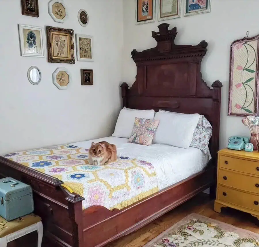 Bed with a colorful quilt in a vintage bedroom with framed art and an old-fashioned phone