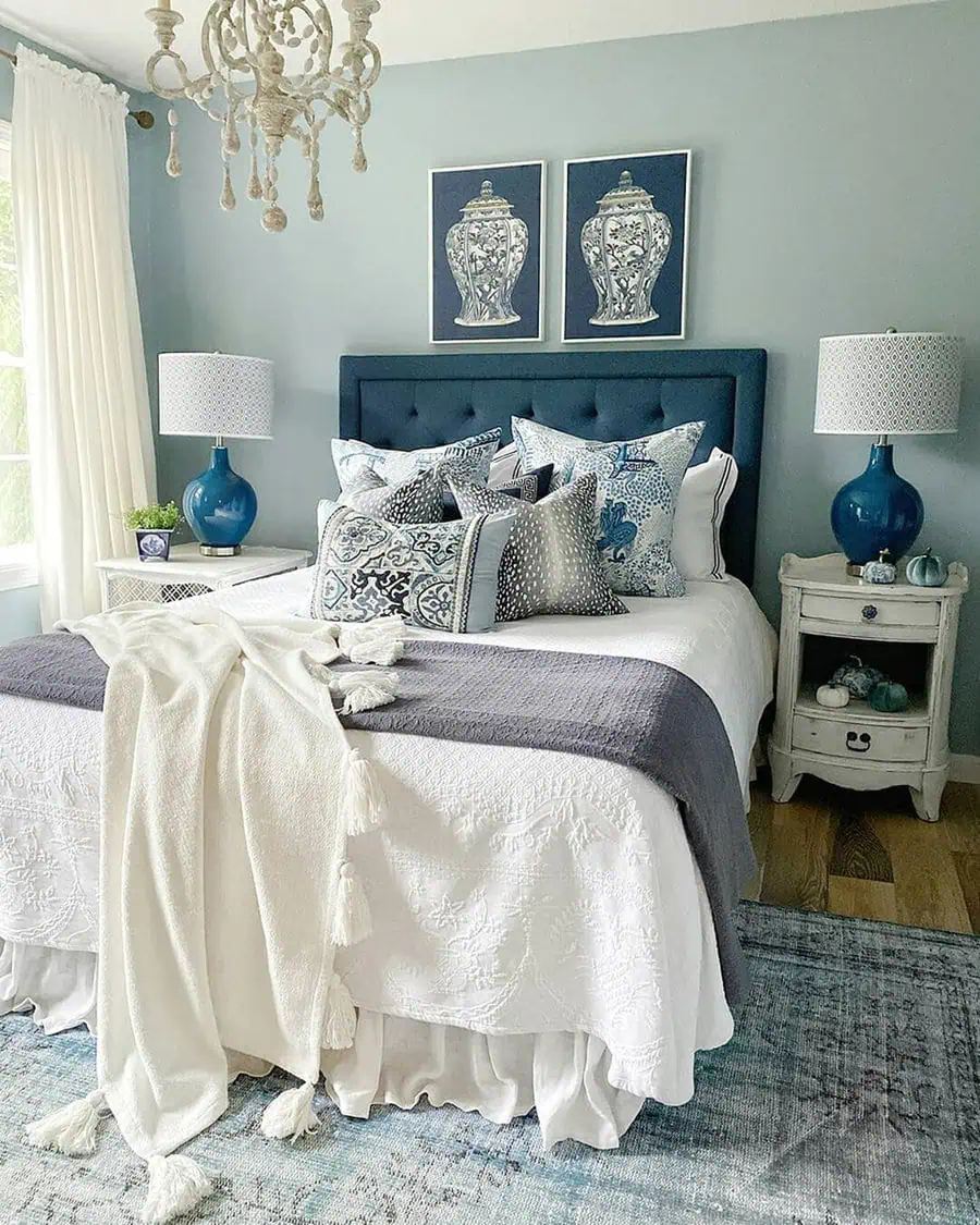 A cozy blue and white bedroom with elegant bedding and decorative table lamps