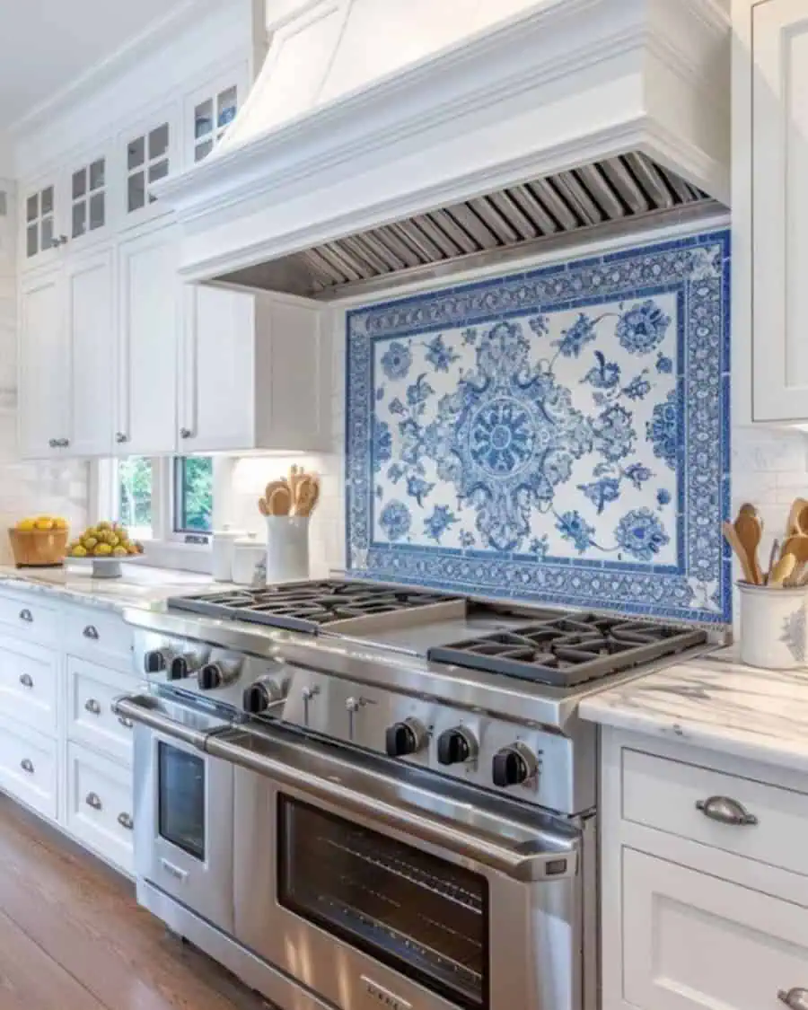 A kitchen with white cabinetry, a large stainless steel stove, and a blue and white decorative backsplash.