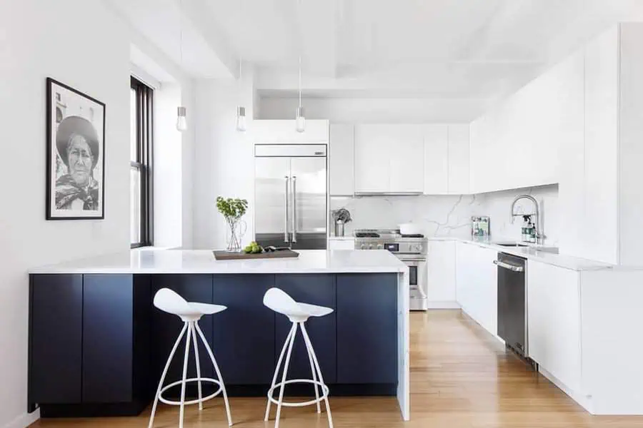 Modern kitchen with dark blue-and-white decor, two white stools, and sleek appliances